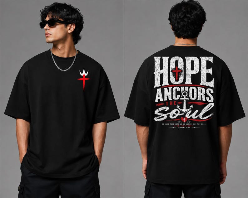 May include: A black short-sleeve t-shirt featuring a small red cross and white crown graphic on the front left chest. The back displays large white text reading HOPE ANCHORS THE SOUL with a central anchor, red cross, and small red heart.