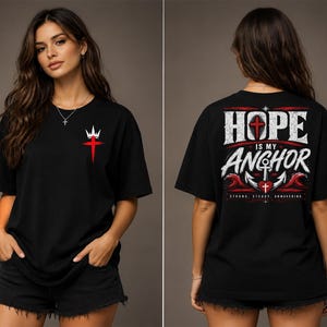 May include: A black short-sleeve t-shirt featuring a small red cross with a white crown on the front chest. The back displays the text HOPE IS MY ANCHOR in white, with a large anchor, a red heart, and red waves, plus the text STRONG, STEADY, UNWAVERING.
