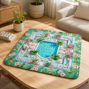 May include: A square game mat featuring a vibrant tropical pool scene with light blue lounge furniture, pink flowers, and green palm leaves. The design includes a central swimming pool surrounded by patio tiles and scattered mahjong tiles.