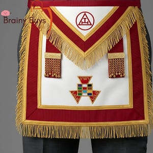 May include: A white, red, and gold Masonic apron with fringe and decorative elements. The apron features a red border, gold fringe, and various symbols, including a triangle with a letter inside and a multi-colored geometric design.
