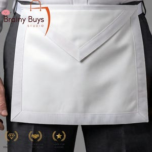 May include: A white apron with a V-shaped bib and a ribbed border. The apron is made of a smooth, possibly satin-like material. The apron is worn over dark pants. The logo "Brainy Buys Studio" is visible in the upper left corner.