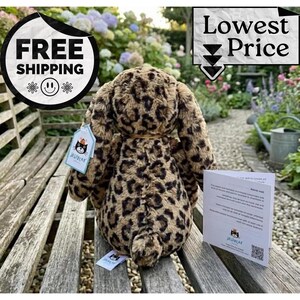 May include: A soft toy leopard-print bunny with long, floppy ears, sitting on a wooden bench. The plush animal has a tag attached. The image also includes a "Lowest Price" and "Free Shipping" graphic.