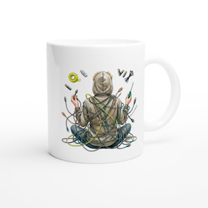 May include: White ceramic mug featuring an illustration of a person tangled in colorful wires, holding tools. The person is wearing a hoodie. The word "VIK" is written on the mug.