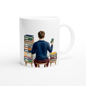 May include: White ceramic mug with an illustration of a person at a desk, surrounded by binders and holding a green device. The person wears a blue sweater and red trousers. The mug has a white handle.