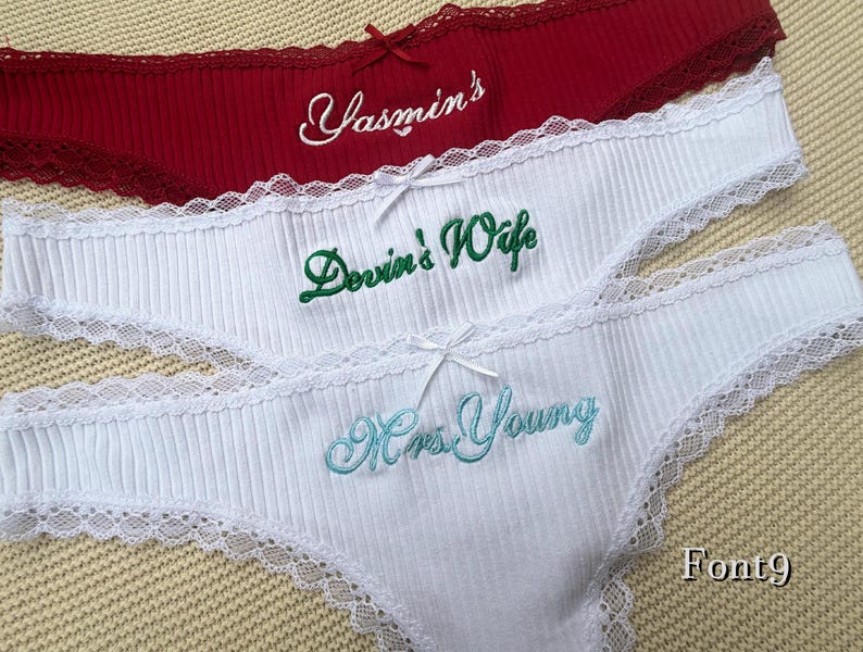 May include: Three pairs of ribbed underwear with lace trim and small bows. The top pair is dark red with white embroidery reading Yasmin's. The middle pair is white with green embroidery reading Devin's Wife. The bottom pair is white with light blue embroidery reading Mrs. Young.