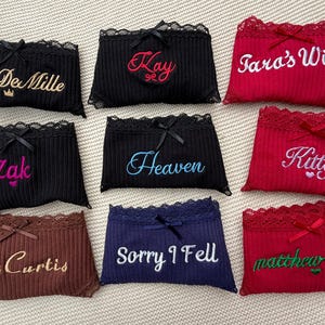 May include: A collection of nine ribbed underwear pairs in black, red, brown, and navy blue, each featuring lace trim, a small center bow, and custom embroidery including names like Mrs DeMille, Kay, Tara's Wife, Zak, Heaven, Kitty, Mrs Curtis, Sorry I Fell, and matthew's wife.