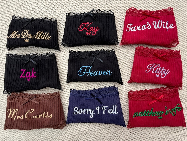 May include: A collection of nine ribbed underwear pairs in black, red, brown, and navy blue, each featuring lace trim, a small center bow, and custom embroidery including names like Mrs DeMille, Kay, Tara's Wife, Zak, Heaven, Kitty, Mrs Curtis, Sorry I Fell, and matthew's wife.