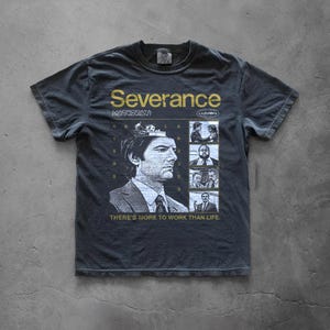 May include: A charcoal grey short-sleeve t-shirt featuring a graphic print from the show Severance. The design includes the text Severance, Macrodata Refinement, and There's More To Work Than Life, alongside a portrait and four smaller scene panels.