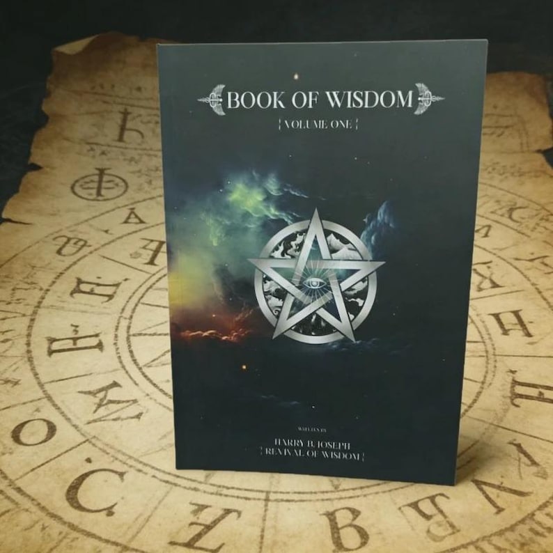 Puede incluir: Un libro negro titulado Book of Wisdom Volume One con un pentagrama plateado y un gr&aacute;fico de un ojo en la portada. La portada presenta un fondo tipo nebulosa con tonos verdes, azules y naranjas. El texto Harry B. Joseph Revival of Wisdom est&aacute; impreso.