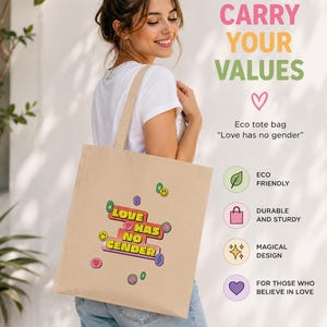 Op de afbeelding: Een beige canvas draagtas met een kleurrijke afbeelding met de tekst "LOVE HAS NO GENDER", omringd door kleine iconen zoals smileys, hartjes en bliksemschichten. De tas bevat de tekst "CARRY YOUR VALUES" en "Eco tote bag".