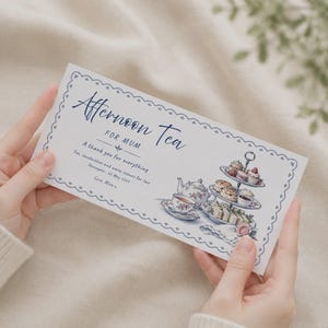 Könnte beinhalten: Ein rechteckiger weißer Geschenkgutschein mit blauem Wellenrand, der den Text Afternoon Tea FOR MUM, A thank you for everything, Tea, sandwiches and warm scones for two, Harrogate - 22 May 2024, Love, Alice x sowie eine Aquarellillustration eines Teeservices zeigt.
