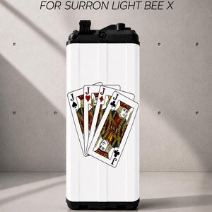 May include: A white battery sticker for a Surron Light Bee X featuring a graphic of four playing cards, specifically the Jacks of spades, hearts, diamonds, and clubs. The text BATTERY STICKERS FOR SURRON LIGHT BEE X is printed above the battery unit.