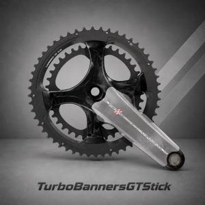 Könnte beinhalten: Ein schwarzes Fahrrad-Kurbelgarnitur mit einem silbernen Arm, mit einem gezahnten Kettenblatt und dem Text "SUPER RECORD CAMPAGNOLO". Die Kurbelgarnitur befindet sich vor einem grauen Hintergrund mit dem Text "TurboBannersGTStick".