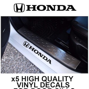 Könnte beinhalten: Ein Set aus fünf schwarzen Vinyl-Aufklebern mit dem Honda-Logo und Schriftzug. Die Aufkleber sind für Fahrzeugtürschwellen konzipiert und hier auf einer silbernen Einstiegsleiste in einem weißen Auto mit schwarzem Innenraum abgebildet.