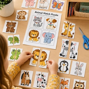 Op de afbeelding: Een kind legt een "Animal Match Puzzle" op een houten tafel. De puzzel toont kleurrijke, cartoonachtige dierenhelften, waaronder een leeuw, een zebra en een pinguïn. De tekst "Animal Match Puzzle" is zichtbaar op een wit vel.
