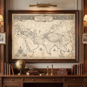 May include: A framed vintage-style map titled A NEW AND ACCURATE MAPP OF THE ANCIENT SILK ROAD AND TRADE ROUTES BETWEEN THE ORIENT AND THE OCCIDENT, featuring detailed geographical outlines, compass rose, and ships on a parchment-coloured background.