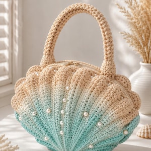 May include: A crochet handbag shaped like a seashell, with a beige and turquoise gradient. The bag is embellished with faux pearls and has a handle and zip closure. The design evokes a seaside theme, with a unique and decorative appearance.