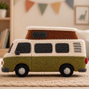 May include: A crocheted toy van featuring an olive green lower body, a cream upper section, and a brown roof. The vehicle has dark gray windows, black wheels with light gray centers, and a small red taillight. The design includes a pop-top roof.