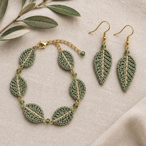 Può includere: Un set di gioielli composto da un bracciale e un paio di orecchini pendenti. Ogni pezzo presenta motivi a foglia realizzati all'uncinetto in verde salvia con una venatura centrale in filo beige, arricchiti da piccole perline verdi e ganci.