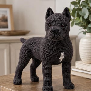 May include: A dark charcoal grey crochet dog figurine standing in a profile pose. The handmade stuffed animal features a textured yarn surface, pointed ears, dark brown eyes, a black nose, and a small white patch of yarn on its chest area.