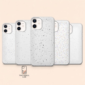 Puede incluir: Colección de cinco fundas blancas para teléfono con diseños moteados. Las fundas tienen un acabado brillante y están dispuestas en fila. El logotipo de The Shell Lab es visible en la parte inferior. Para smartphones.