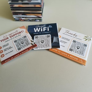 Może przedstawiać: Trzy kwadratowe karty z kodami QR. Lewa karta zawiera napis We appreciate YOUR SUPPORT! LEAVE US A REVIEW. Środkowa karta zawiera napis Guest WiFi SCAN TO CONNECT. Prawa karta zawiera napis Thanks FOR SUPPORTING OUR BUSINESS! SCAN TO LEAVE A REVIEW. Za nimi widoczny jest stos kart.