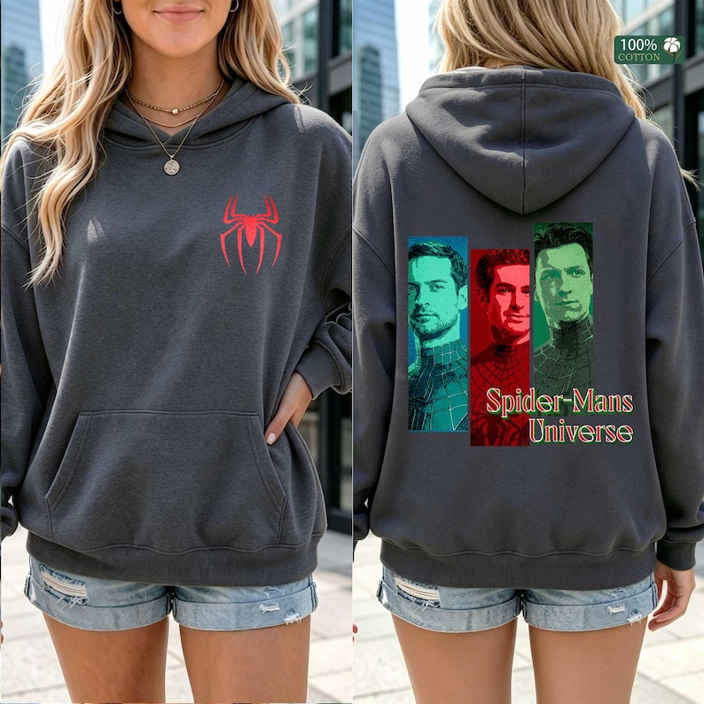May include: A charcoal gray hooded sweatshirt featuring a red spider logo on the front chest. The back displays three vertical rectangular portraits of different figures in blue, red, and green tones with the text Spider-Mans Universe below.