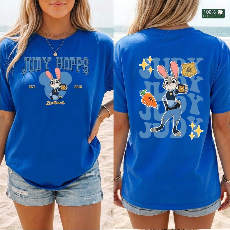 Pu&ograve; includere: Una t-shirt blu reale con una grafica di Judy Hopps di Zootropolis. Il davanti mostra il testo JUDY HOPPS EST. 2016 con un'icona del personaggio. Il retro presenta una grande illustrazione di Judy Hopps, una carota, un distintivo e delle stelle.