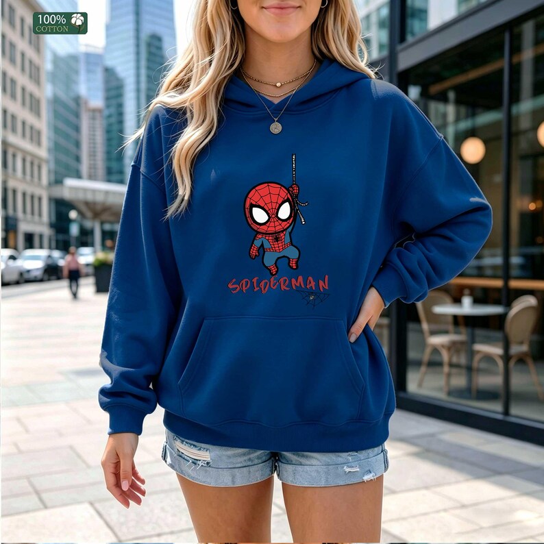 Op de afbeelding: Een marineblauwe hoodie met een cartoon Spider-Man ontwerp. De afbeelding toont een rood en blauw Spider-Man karakter dat aan een web hangt, met het woord "SPIDERMAN" in het rood eronder. De hoodie is gemaakt van 100% katoen.