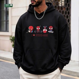 May include: A black hooded sweatshirt featuring a graphic print of four small Spider-Man characters performing different activities, including eating, lifting weights, hanging, and skateboarding, with the text I heart SPIDER-MAN below them.