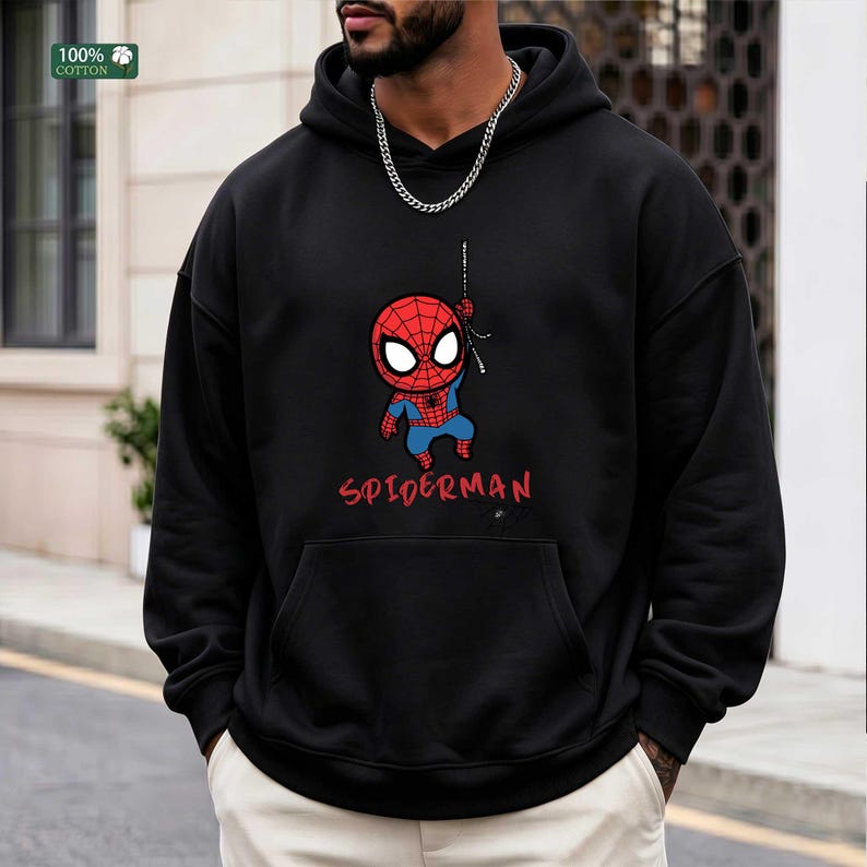 Op de afbeelding: Zwarte hoodie met een cartoon Spider-Man ontwerp. De afbeelding toont Spider-Man in zijn klassieke rood-blauwe pak, met het woord "SPIDERMAN" in rood eronder. Gemaakt van 100% katoen.