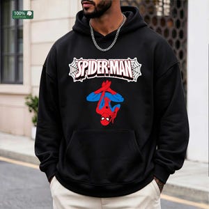 May include: Black hooded sweatshirt with a Spider-Man design. The graphic shows the Spider-Man logo in white with red text and a red and blue Spider-Man figure. The sweatshirt is made of 100% cotton.