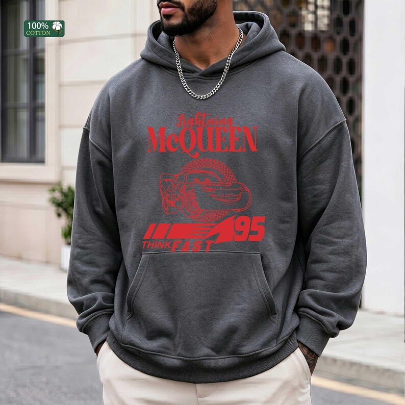 Pu&ograve; includere: Felpa con cappuccio grigio scuro con grafica rossa. La grafica include il testo "Alexander McQueen", un disegno di serpente e il numero "95". La felpa ha una tasca frontale e un cappuccio con coulisse. 100% cotone.