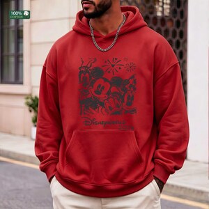 Puede incluir: Sudadera con capucha roja con un gr&aacute;fico negro que presenta a Mickey Mouse, Minnie Mouse, Donald Duck y Goofy, con fuegos artificiales y el texto "Disneyworld 2023". La sudadera tiene un bolsillo delantero y una etiqueta "100% Algod&oacute;n".