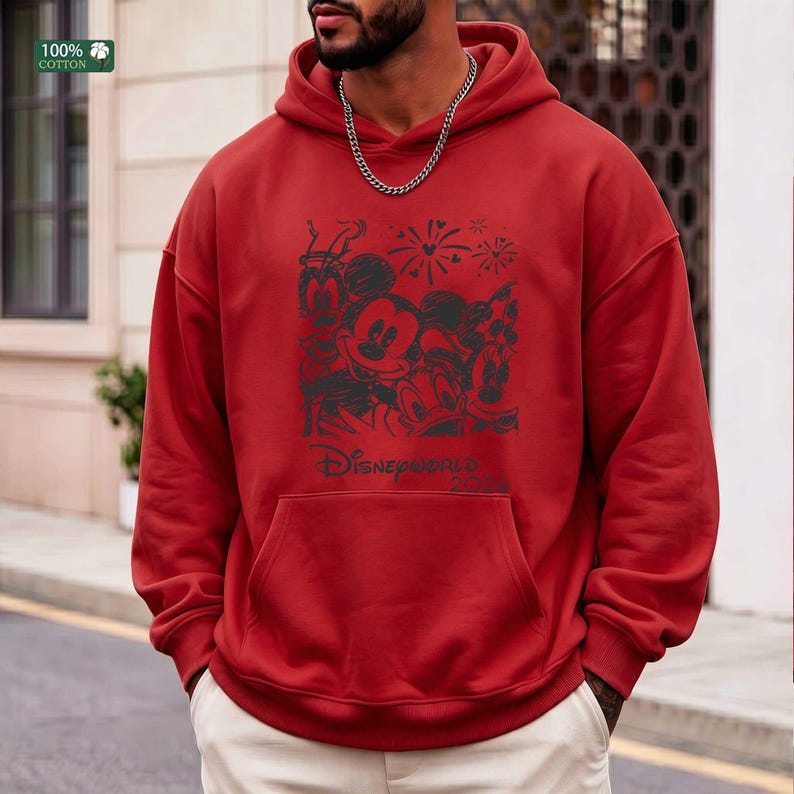 Puede incluir: Sudadera con capucha roja con un gr&aacute;fico negro que presenta a Mickey Mouse, Minnie Mouse, Donald Duck y Goofy, con fuegos artificiales y el texto "Disneyworld 2023". La sudadera tiene un bolsillo delantero y una etiqueta "100% Algod&oacute;n".