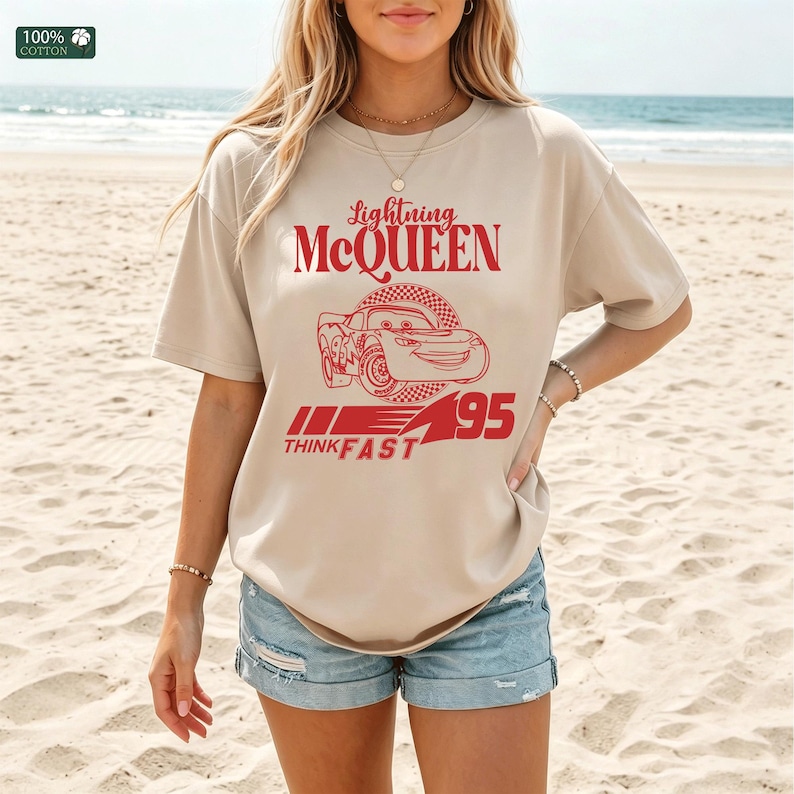 Pu&ograve; includere: T-shirt beige con grafica rossa di Saetta McQueen del film Cars. Il design include la scritta "Lightning McQueen", un'illustrazione di auto, "95" e "Think Fast". La maglietta &egrave; realizzata in 100% cotone.