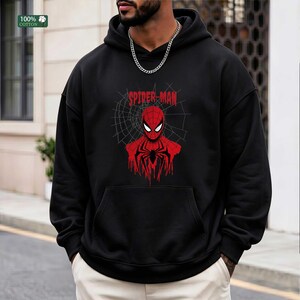 May include: Black hooded sweatshirt featuring a red Spider-Man graphic. The graphic includes the Spider-Man logo and a web design. The sweatshirt is made of 100% cotton.