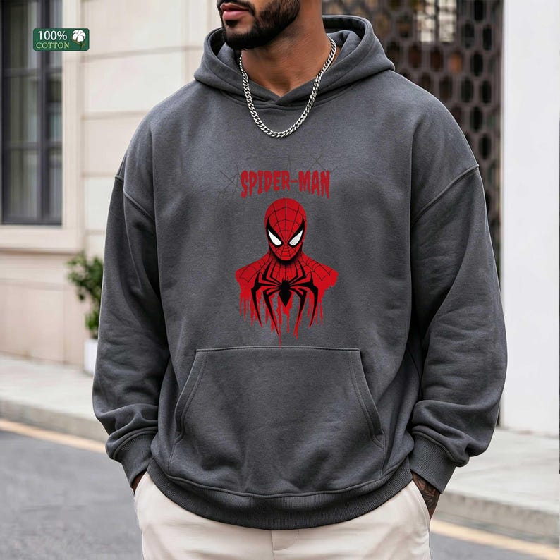 May include: Dark gray hoodie with a red Spider-Man graphic. The graphic includes the words "SPIDER-MAN" above a stylized image of the superhero's face and torso. The hoodie has a front pocket and a hood.