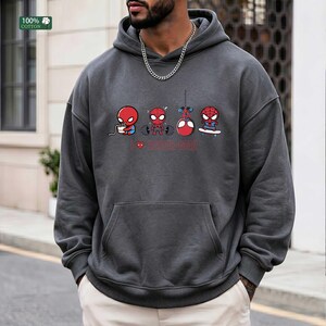 May include: A charcoal gray hooded sweatshirt featuring a graphic print of four small Spider-Man characters engaged in different activities, including eating, lifting weights, hanging, and skateboarding, with the text I heart Spider-Man.