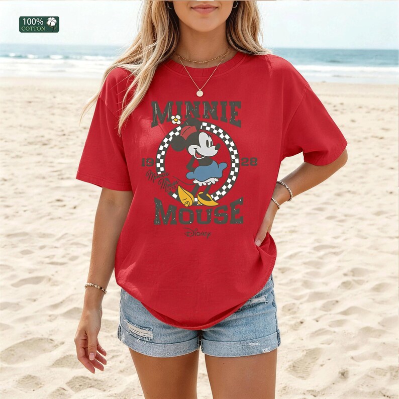 May include: Red t-shirt featuring a Minnie Mouse graphic. The graphic includes the text "MINNIE MOUSE" and the years "1928" and "Disney". The shirt is made of 100% cotton.