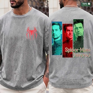 May include: A grey acid-wash t-shirt featuring a red spider emblem on the front chest. The back displays three vertical rectangular panels with portraits of three different figures, accompanied by the text Spider-Mans Universe in red and green.