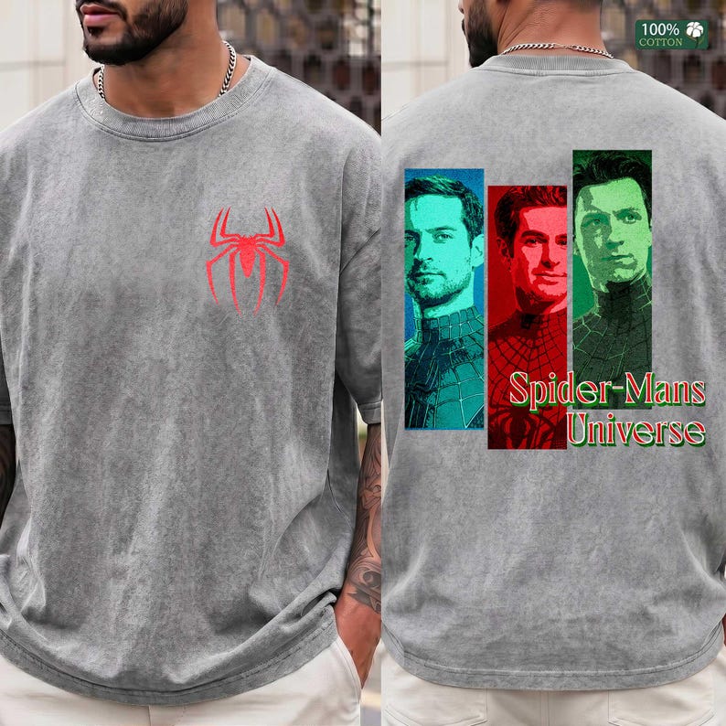 May include: A grey acid-wash t-shirt featuring a red spider emblem on the front chest. The back displays three vertical rectangular panels with portraits of three different figures, accompanied by the text Spider-Mans Universe in red and green.