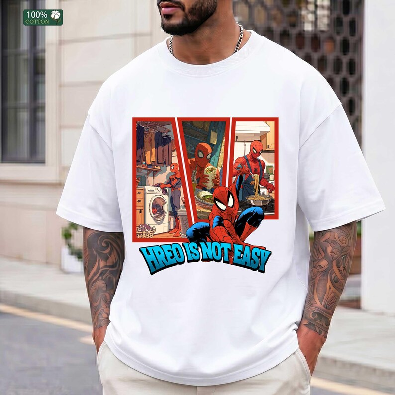 May include: A white short-sleeved t-shirt featuring a graphic print of the character Spider-Man in various domestic settings, including doing laundry and cooking. Below the graphic, the text reads HREO IS NOT EASY in bold blue letters.