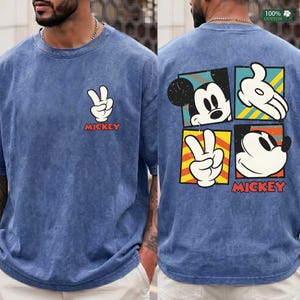 May include: Blue, short-sleeved t-shirt with a peace sign and the word "Mickey" in red. The back features Mickey Mouse in four colorful squares. Made of 100% cotton.