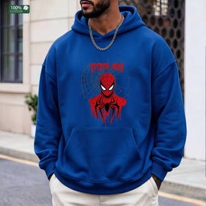 May include: A blue hoodie with a front pocket and a Spider-Man graphic. The graphic features a red Spider-Man design with a web background and the text "SPIDER-MAN" in red. The hoodie is made of 100% cotton.