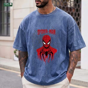 May include: Blue t-shirt with a Spider-Man graphic. The graphic features a red Spider-Man design with a black spider emblem and the words "SPIDER-MAN" in red. The shirt is made of 100% cotton.