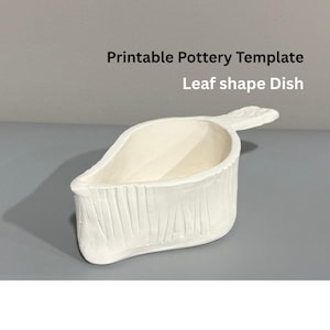 May include: A white, leaf-shaped pottery dish with a textured exterior and a handle. The dish is labeled "Printable Pottery Template" and "Leaf shape Dish". The dish is designed for pottery projects.