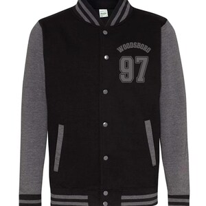 May include: Black and gray letterman jacket with the word "WOODSBORO" and the number "97" in gray lettering. The jacket has gray sleeves, a black body, and gray and white striped trim at the cuffs and waist. It has a button-up front.