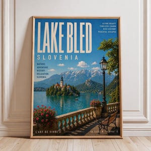 Può includere: Un poster da viaggio incorniciato per il lago di Bled, Slovenia, con una vista panoramica del lago con una chiesa su un'isola, montagne e il testo "LAKE BLED SLOVENIA". Il poster ha una cornice in legno ed è su un muro bianco.