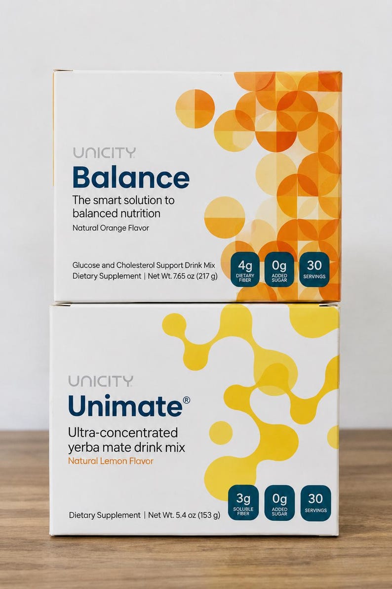 K&ouml;nnte beinhalten: Zwei gestapelte rechteckige Schachteln mit Unicity Nahrungserg&auml;nzungsmitteln. Die obere Schachtel ist Balance, ein Getr&auml;nkepulver mit nat&uuml;rlichem Orangengeschmack, Nettogewicht 217 g. Die untere Schachtel ist Unimate, ein hochkonzentriertes Yerba-Mate-Getr&auml;nkepulver mit nat&uuml;rlichem Zitronengeschmack, Nettogewicht 153 g. Beide Schachteln enthalten 30 Portionen.